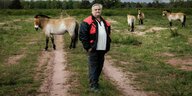 Ein Mann steht auf der grünen Wiese inmitten von altertümlichen Pferden: Tierranger Detlef Baumung und die Przewalski-Pferde in der Döberitzer Heide
