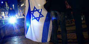 Menschen mit Israelfahne in abendlicher Stadt