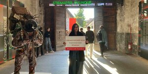 Eine Frau der Bewegung "Woman, Life, Freedom" hält auf Hauptausstellung der Venedig-Biennale ein Plakat hoch, das gegen den iranischen Pavillon gerichtet ist